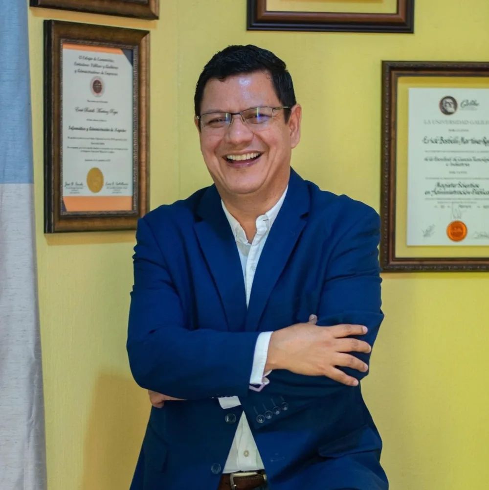 Erick sonriente frente a sus títulos universitarios